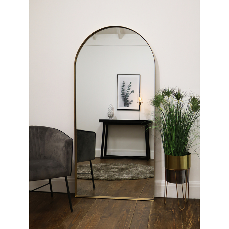 Full length arched gold large metal mirror leaning against wall