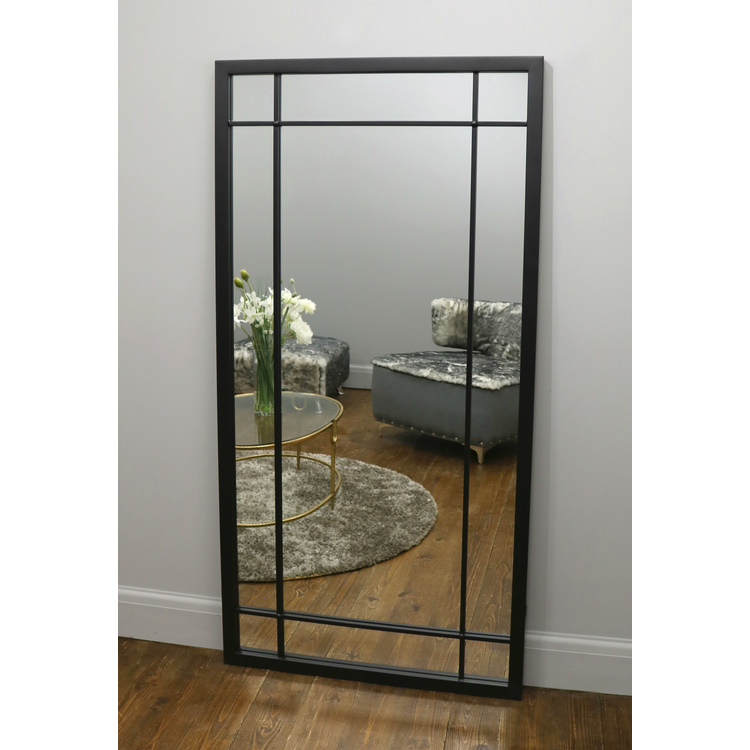 Black industrial full length metal mirror leaning against wall