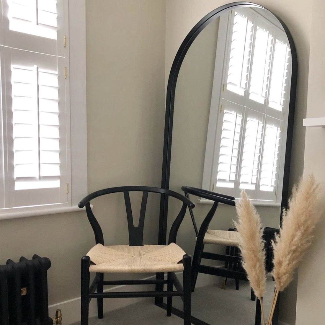 Full length arched black large metal mirror leaning against wall