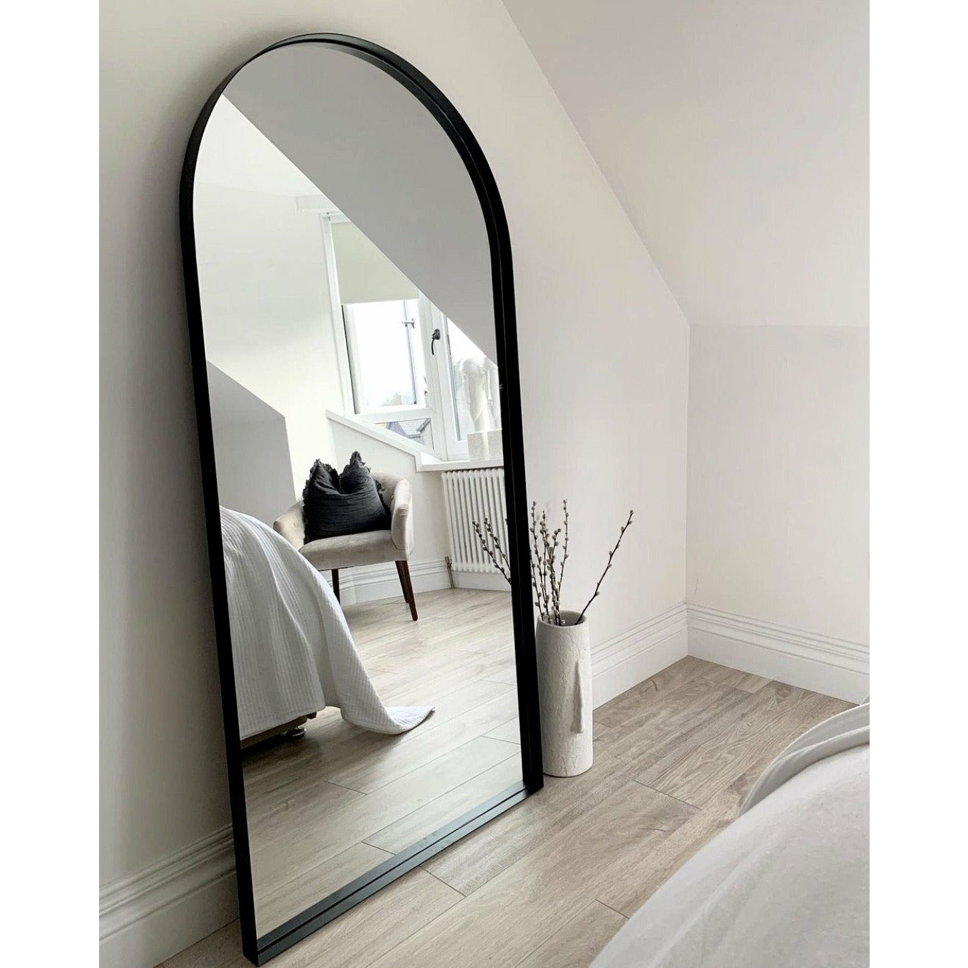 Full length arched black large metal mirror leaning against wall